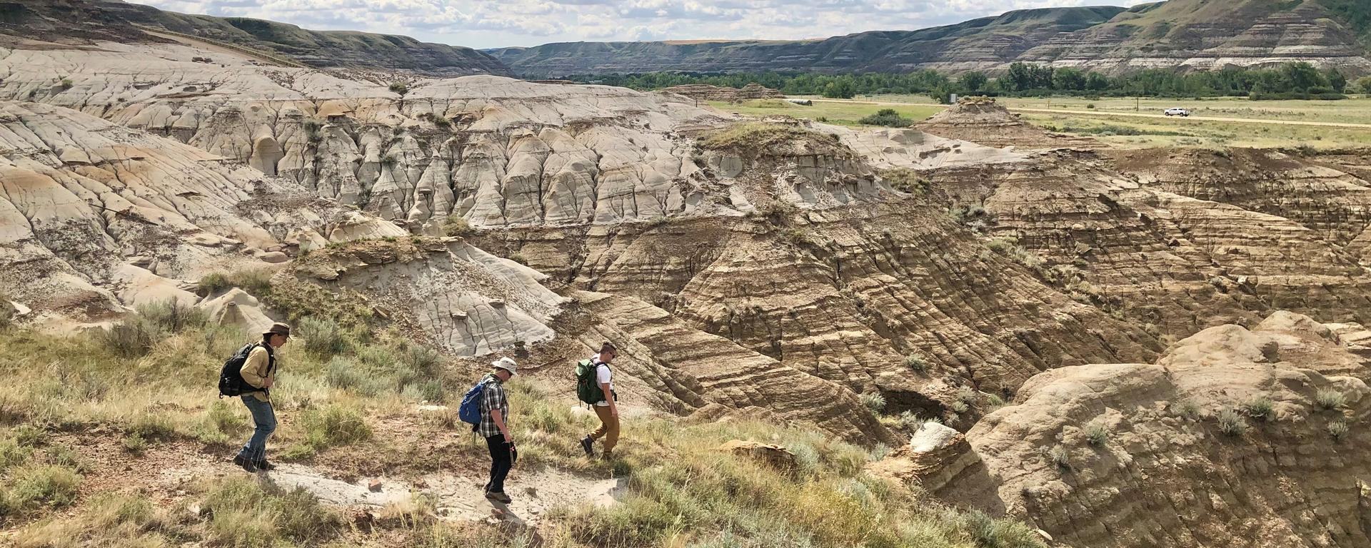Members of the field team explore the geology at the Drumheller field site, including project investigators Dr. Glen Dolphin (left) and Dr. Paul Nesbit (right), as well as Associate Professor (teaching) Dr. Alex Dutchak (centre) from the Department of Geoscience
