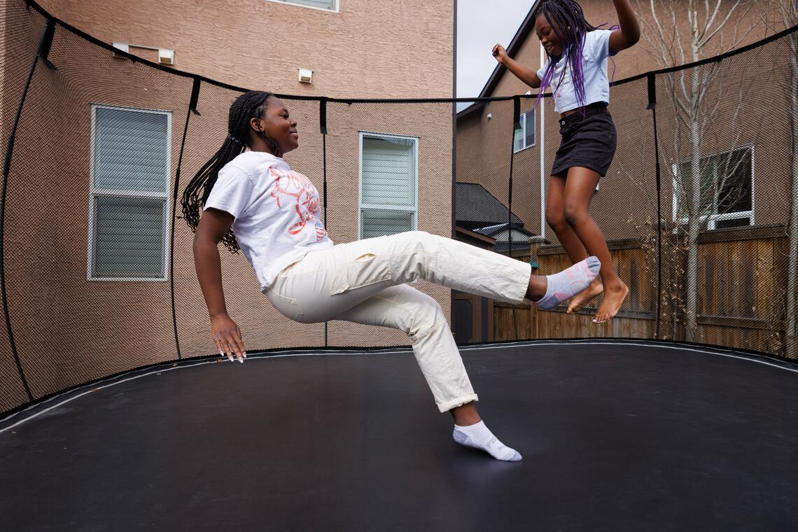 Eleora Ogundare and her younger sister Katriel jump on a trampoline