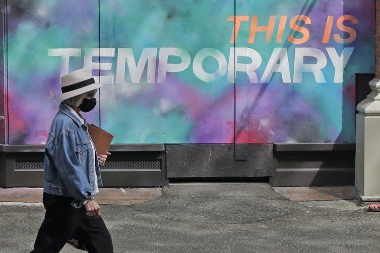 A person walks by a mural on a boarded-up window on April 28, 2020, in Seattle, Wash., where public street art has sprung up all over the city.