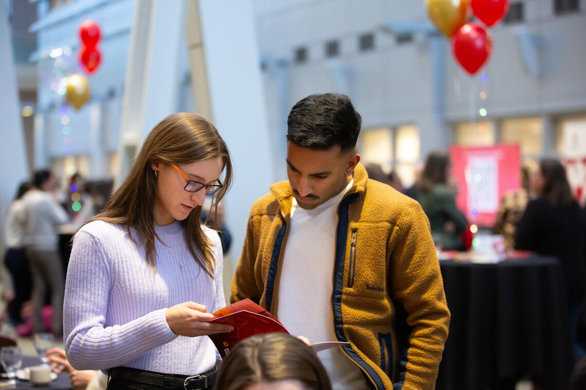 Two people look down at a pamphlet