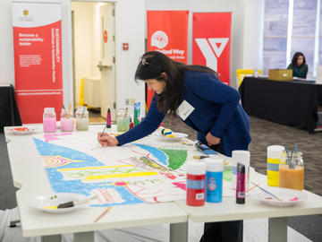 Dr. Veronica Caparas, Faculty of Social Work, adds her artistic contribution to a mural participants collaboratively painted throughout Knowledge to Impact: Igniting Community Engagement in the City Building Design Lab.