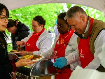 Three volunteers serving Dr. Malinda Smith Vice-Provost (Equity, Diversity and Inclusion), Wendy Benoit (Interim Vice-Provost, Teaching & Learning) and Bruce Evelyn (Vice-Provost, Planning & Resource Allocation) serving pulled pork sandwiches at the President's Stampede Barbecue. to a guest