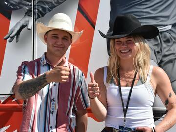 Two people in cowboy hats give the cameras thumbs up