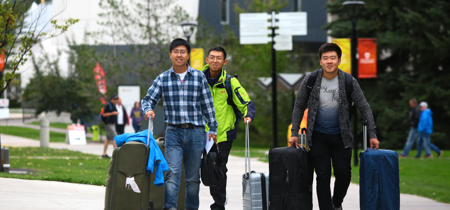 Students with suitcases come to campus