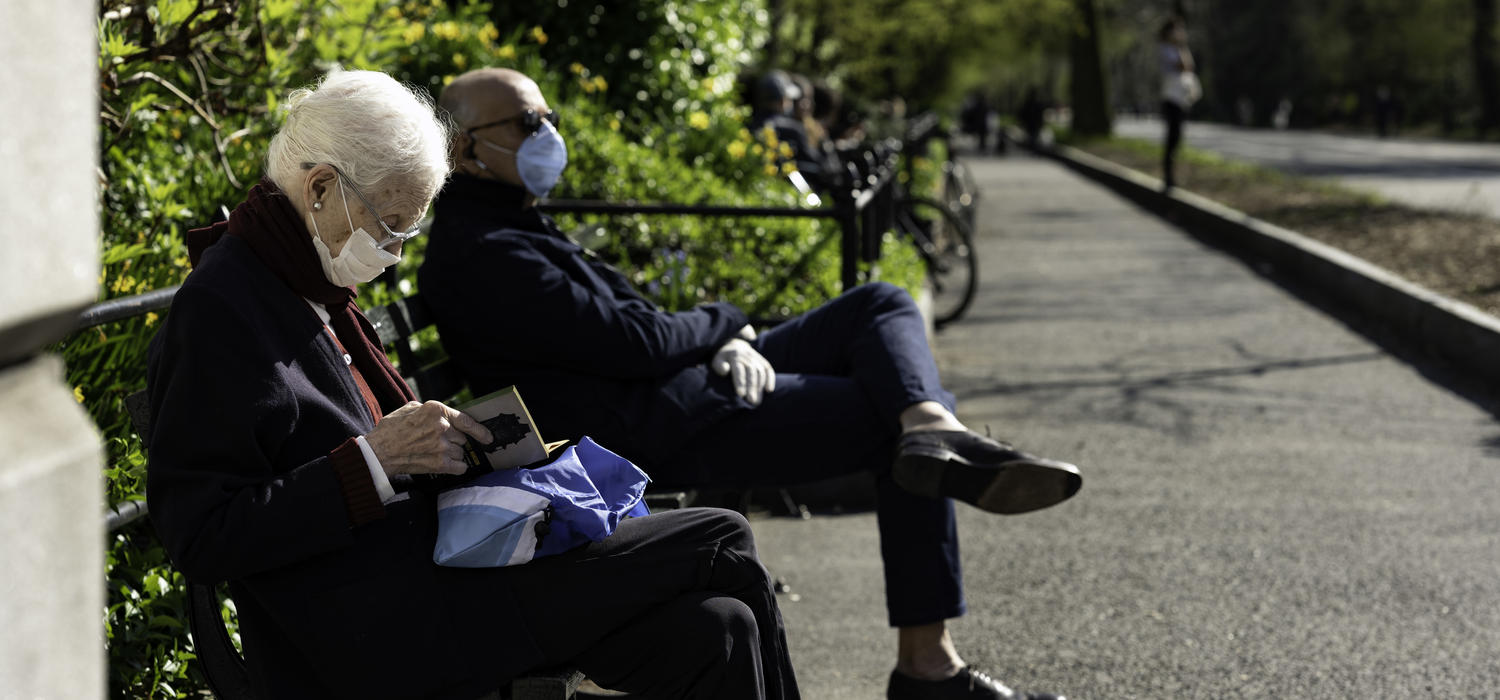 Older adult on park bench with mask on