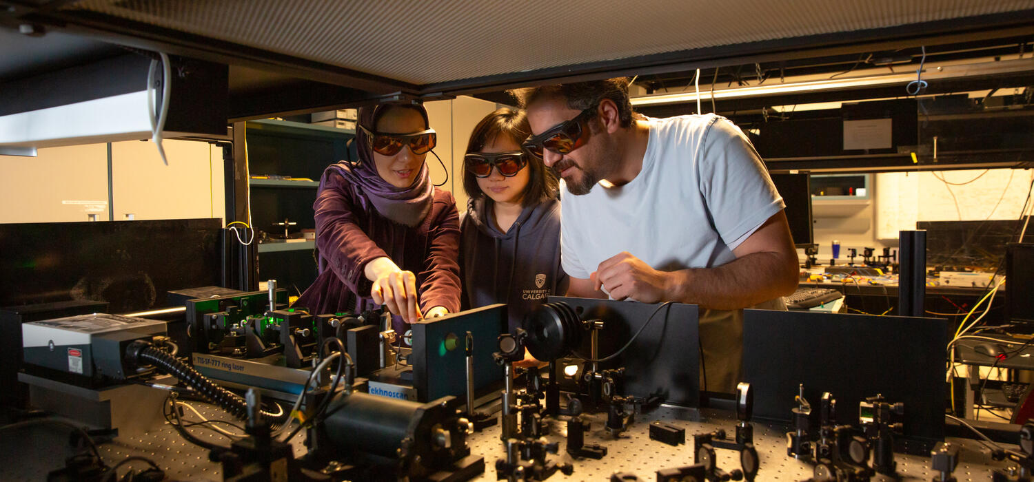 Three people wearing goggles work on a quantum machine