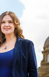 Alumna Jennifer Burgess stands in front of the Alberta legislature building