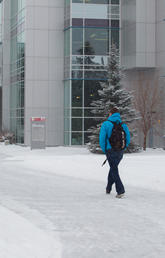 Two people walk in the snow on main campus