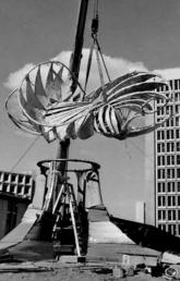 Image of a crane lowering the top of the Norris Sculpture (also known as The Prairie Chicken) onto the base