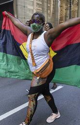 A supporter holds up a flag as she marches down the street celebrating Juneteenth, June 19, 2021, in Chicago, Ill.