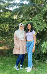 Two first-in-family students standing in front of trees on the university campus