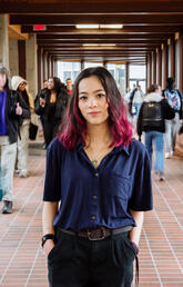 Emilie Lui, a student, stands in a busy hallway with blurred people around them.