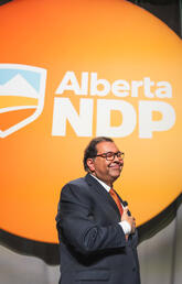 Nenshi standing in front of the Alberta NDP sign