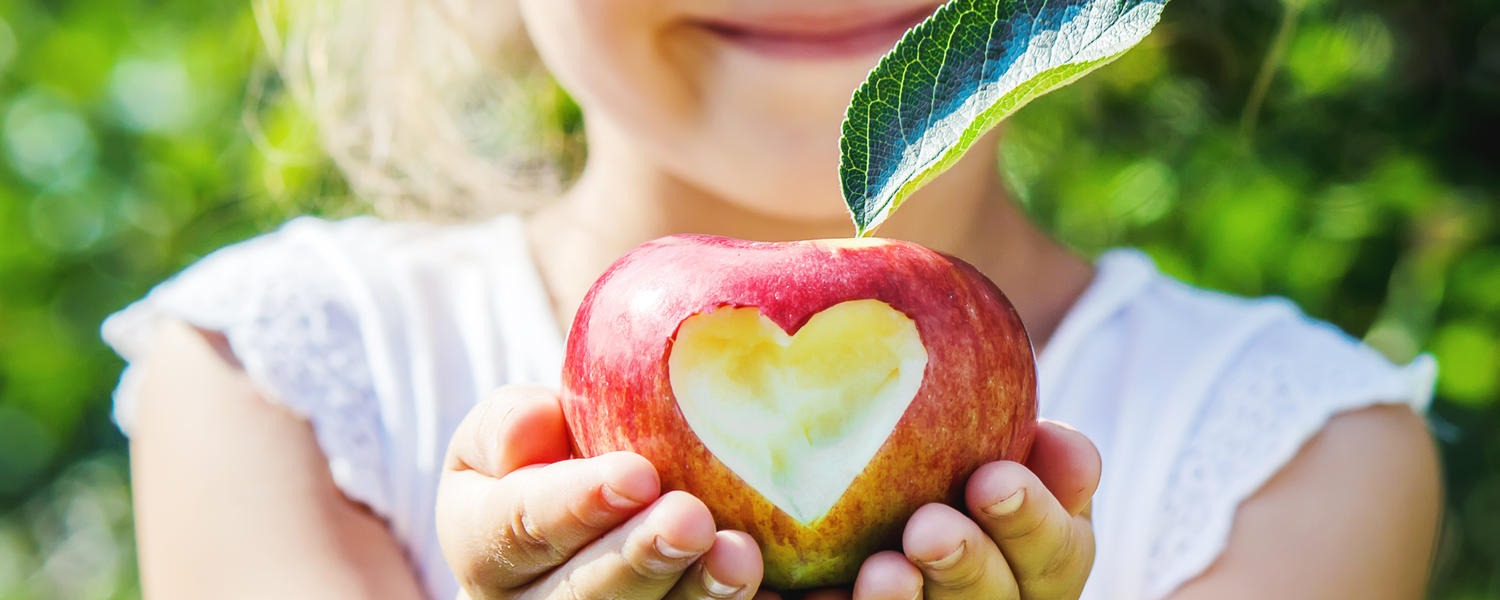 Girl holding apple with a heart carved in it.