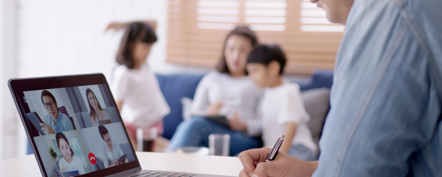 Dad viewing webinar on pc; mom and children on sofa