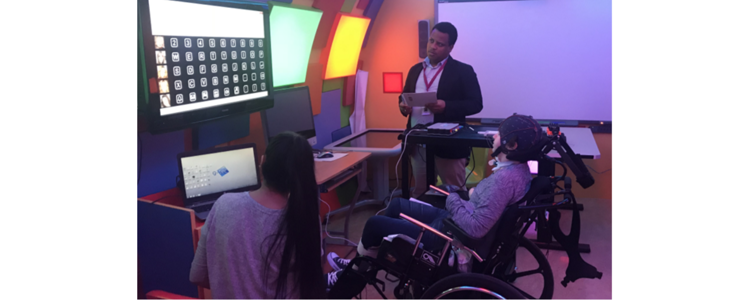 Two researchers take notes as a boy uses a BCI for a spelling experiment