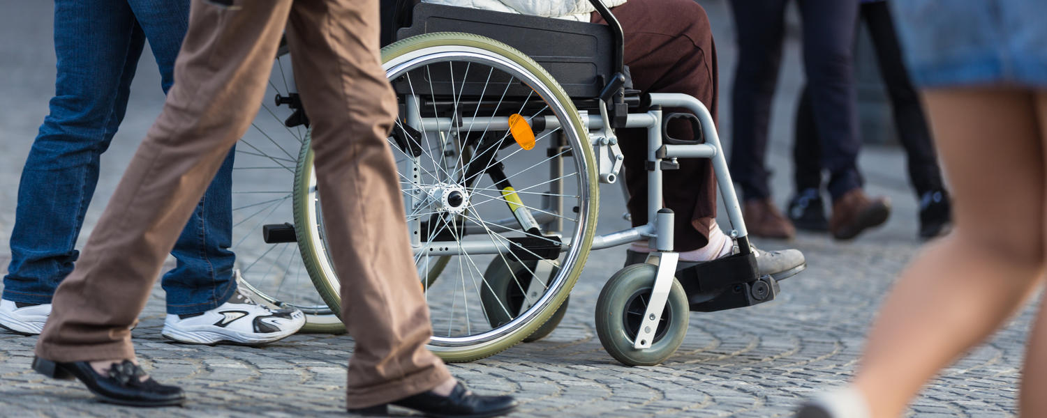 Photo is from the waist down of people walking / utilizing a wheelchair