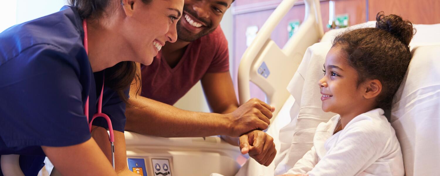 Parent and doctor with child in hospital bed.