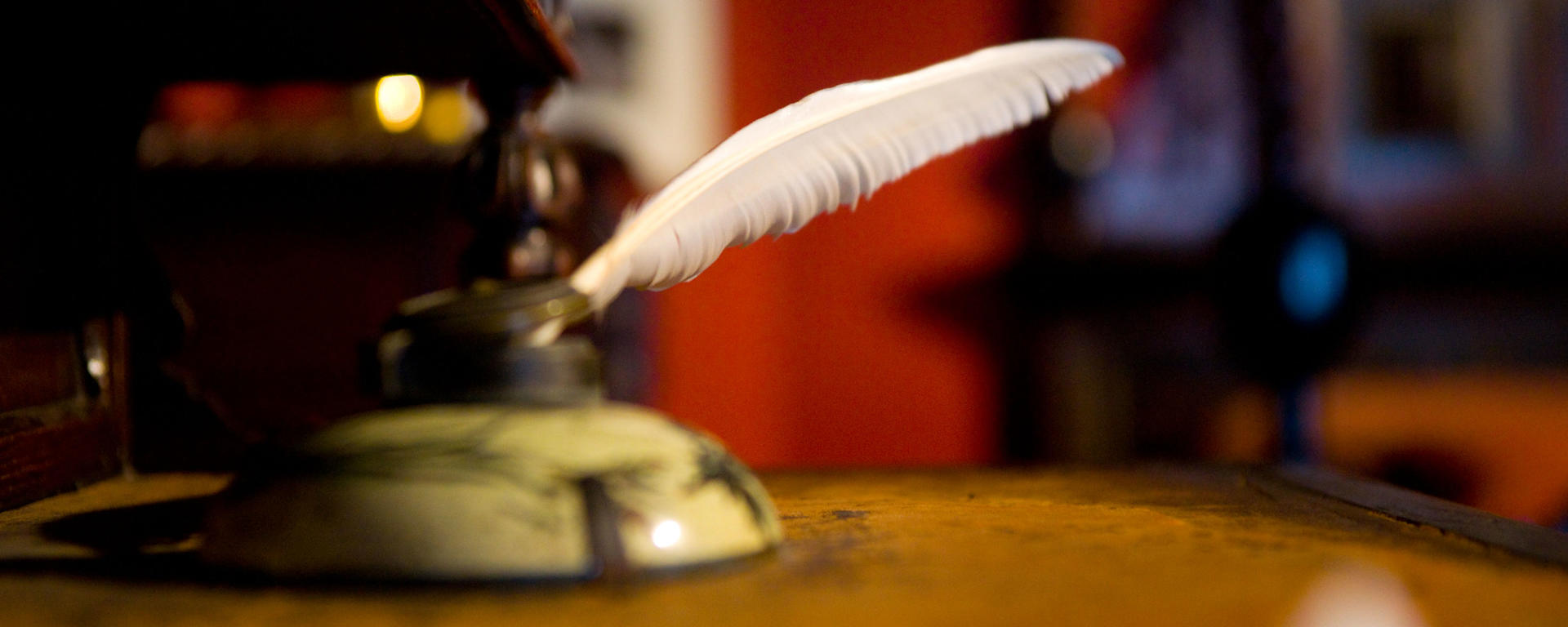 quill in an ink well on an antique desk