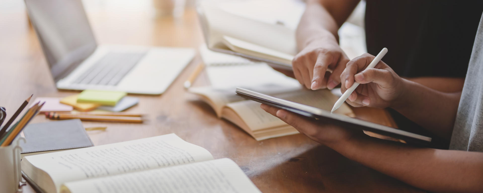 People doing research, pen in hand, textbooks open