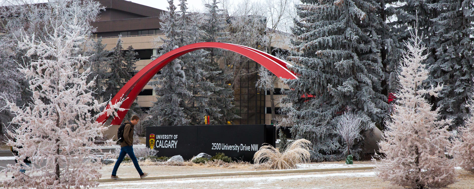 Winter at the U of C Campus with man walking in background in front of red archway