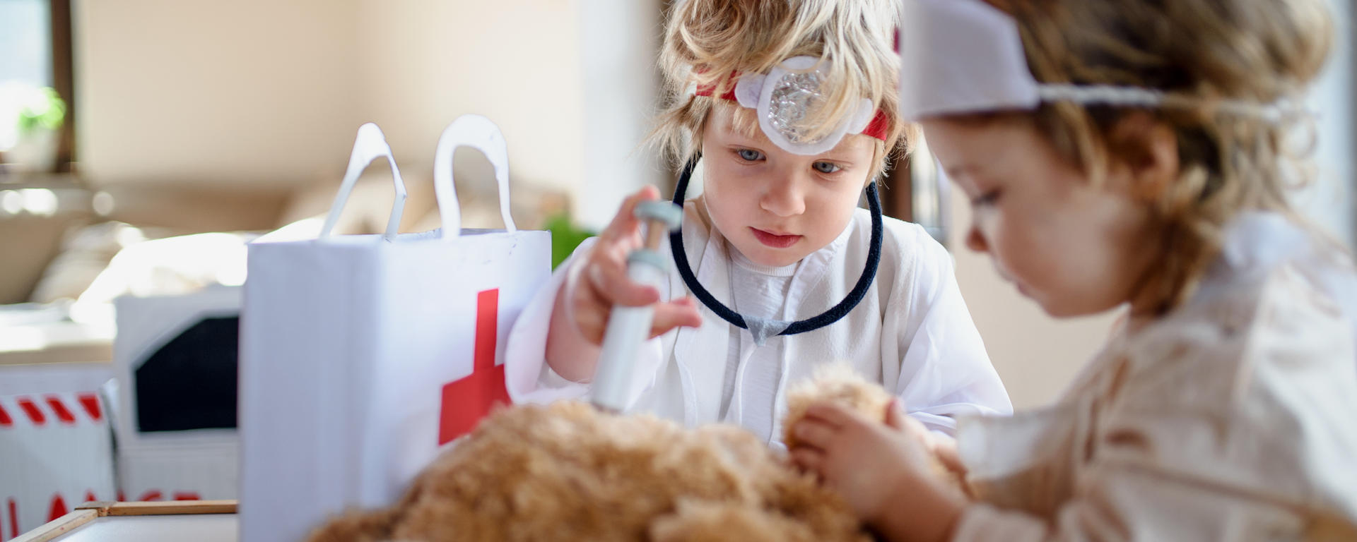 two kids playing doctor with teddy bear