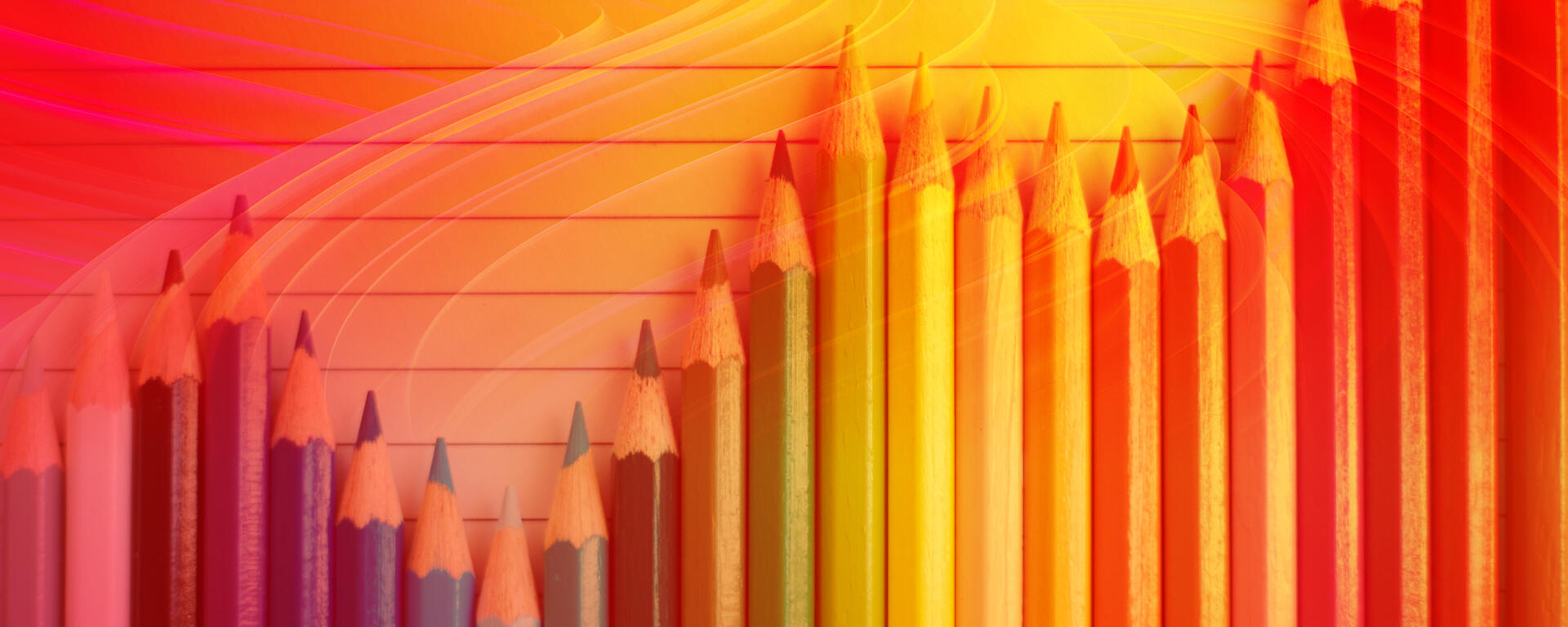 Wavy row of coloured pencils with red and yellow background