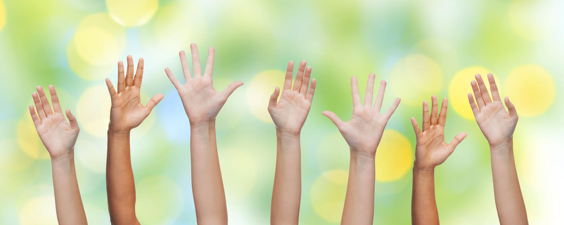 different hands raised in the air with a green bubble effect in the background 