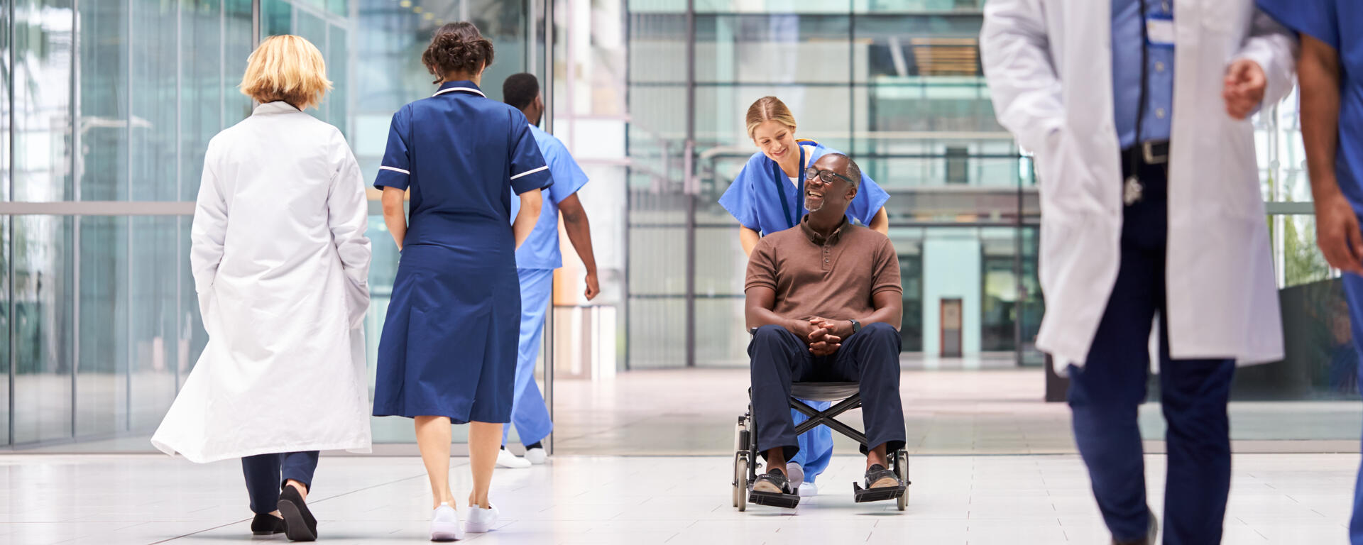Man being pushed in a wheel chair by a nurse in hospital