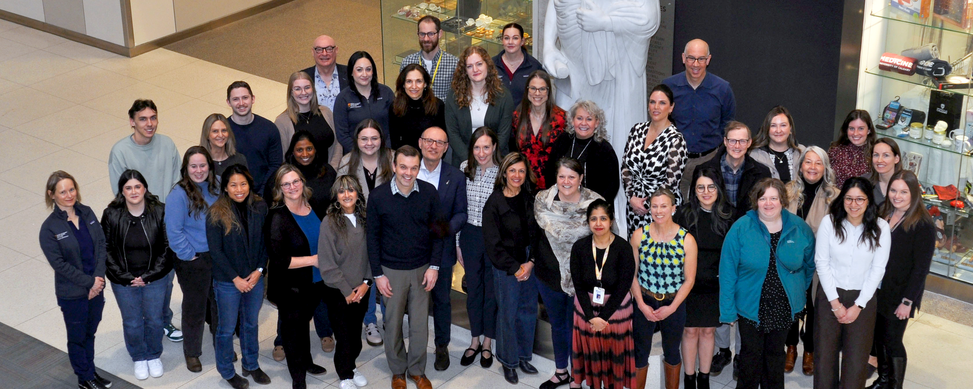 ICDC team photo taken in front of the Hippocrates statue located in the atrium of the Health Sciences Centre building, on the UCalgary Foothills campus