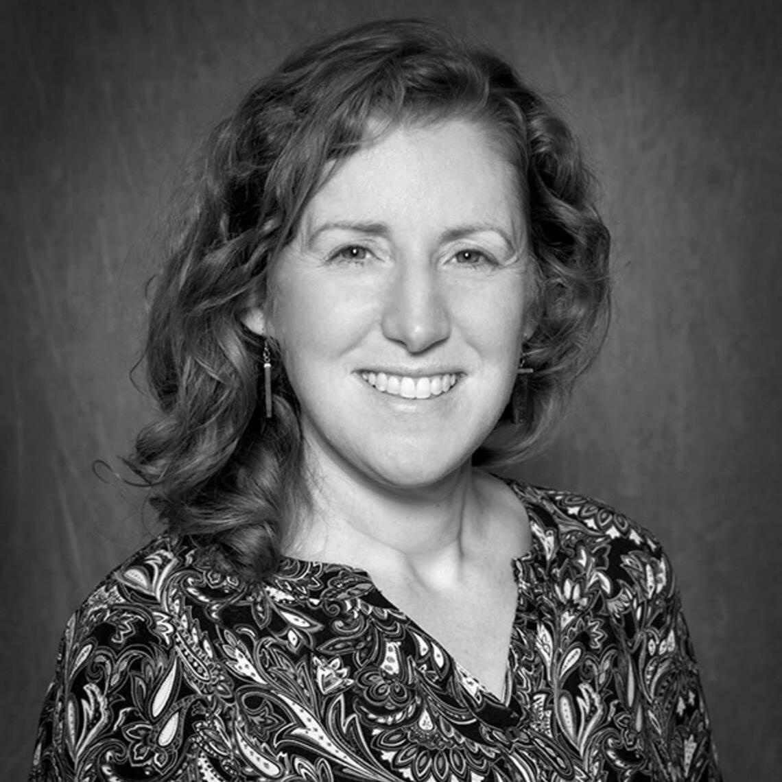 Headshot of a woman with shoulder length wavy hair smiling at the camera