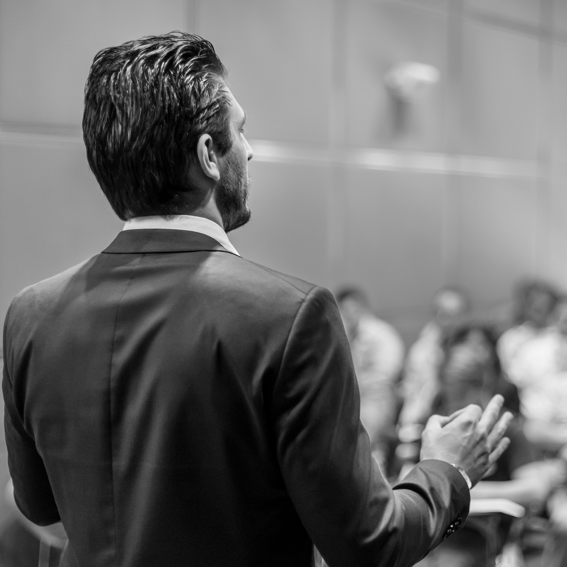 black and white photo of a man standing at the podium facing the crowd
