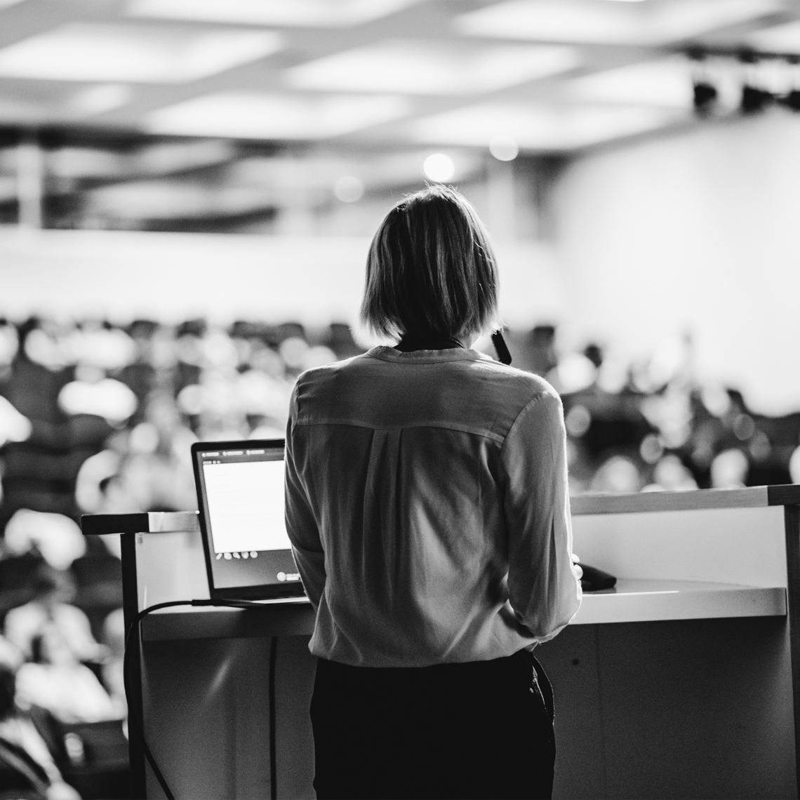 black and white photos of a woman standing at a podium facing the audience