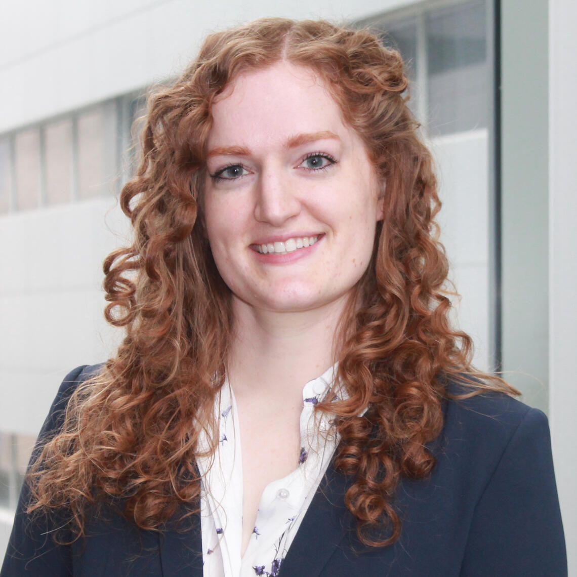 Jane Fletcher, PhD Candidate, smiling in a professional headshot with building in the background