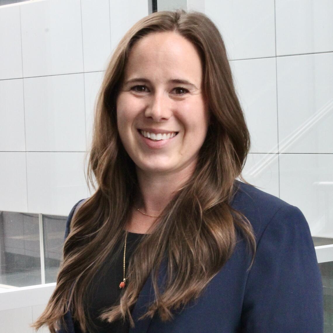 Danielle Fox PhD Candidate, smiling in a professional headshot with a building in the background