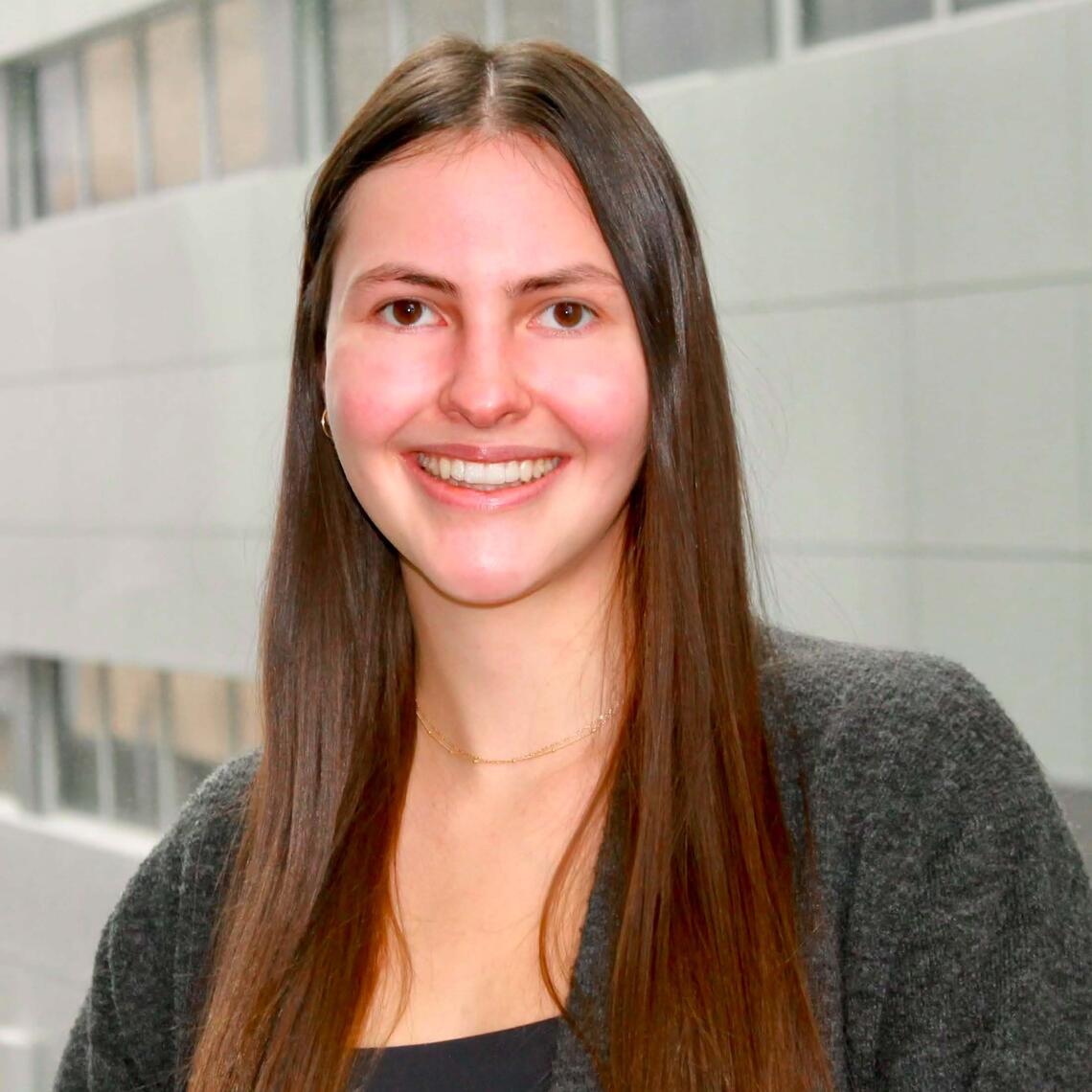 Victoria Riehl-Tonn, PhD Candidate, smiling in a professional headshot with a blurred building background