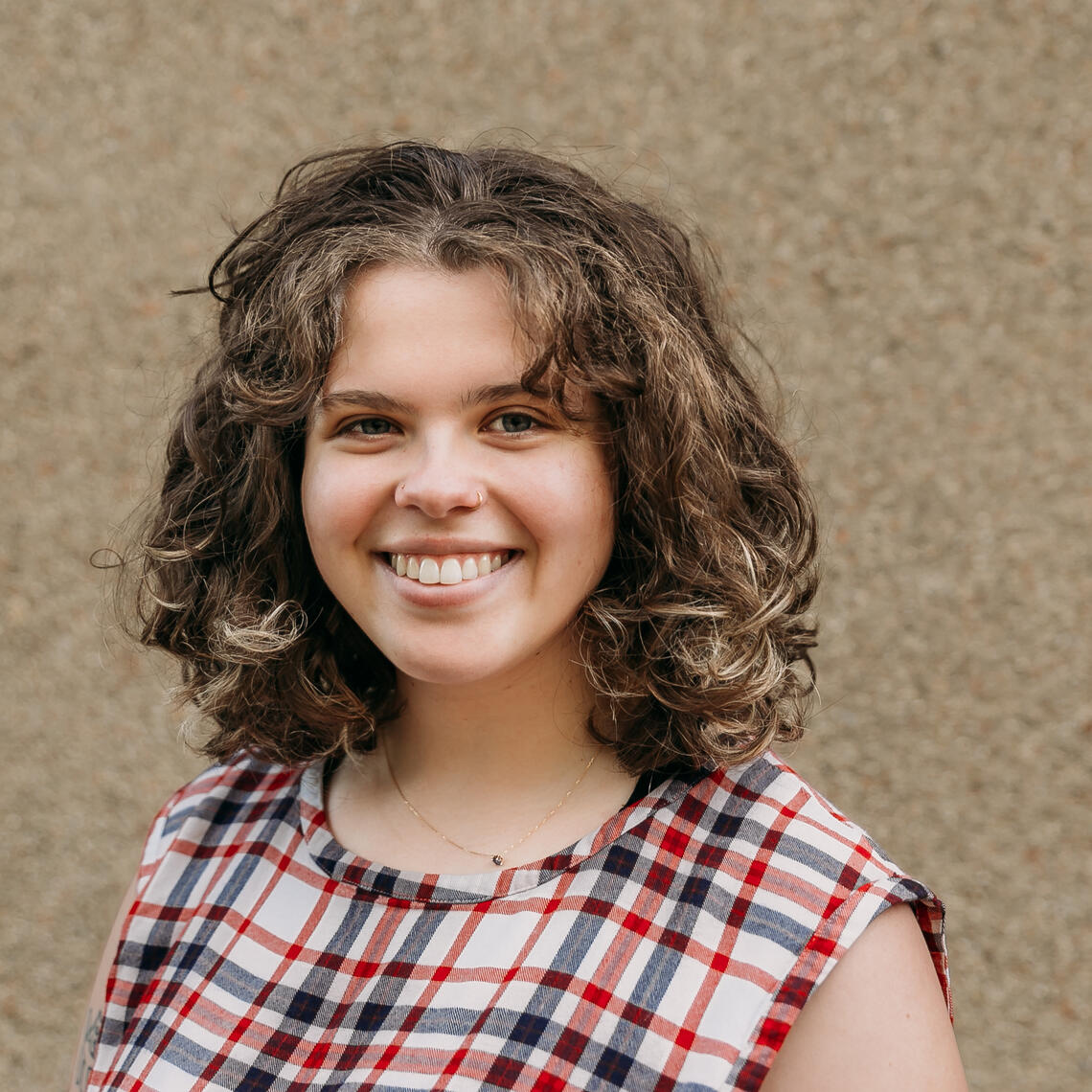 smiling youngv woman with curly brown hair