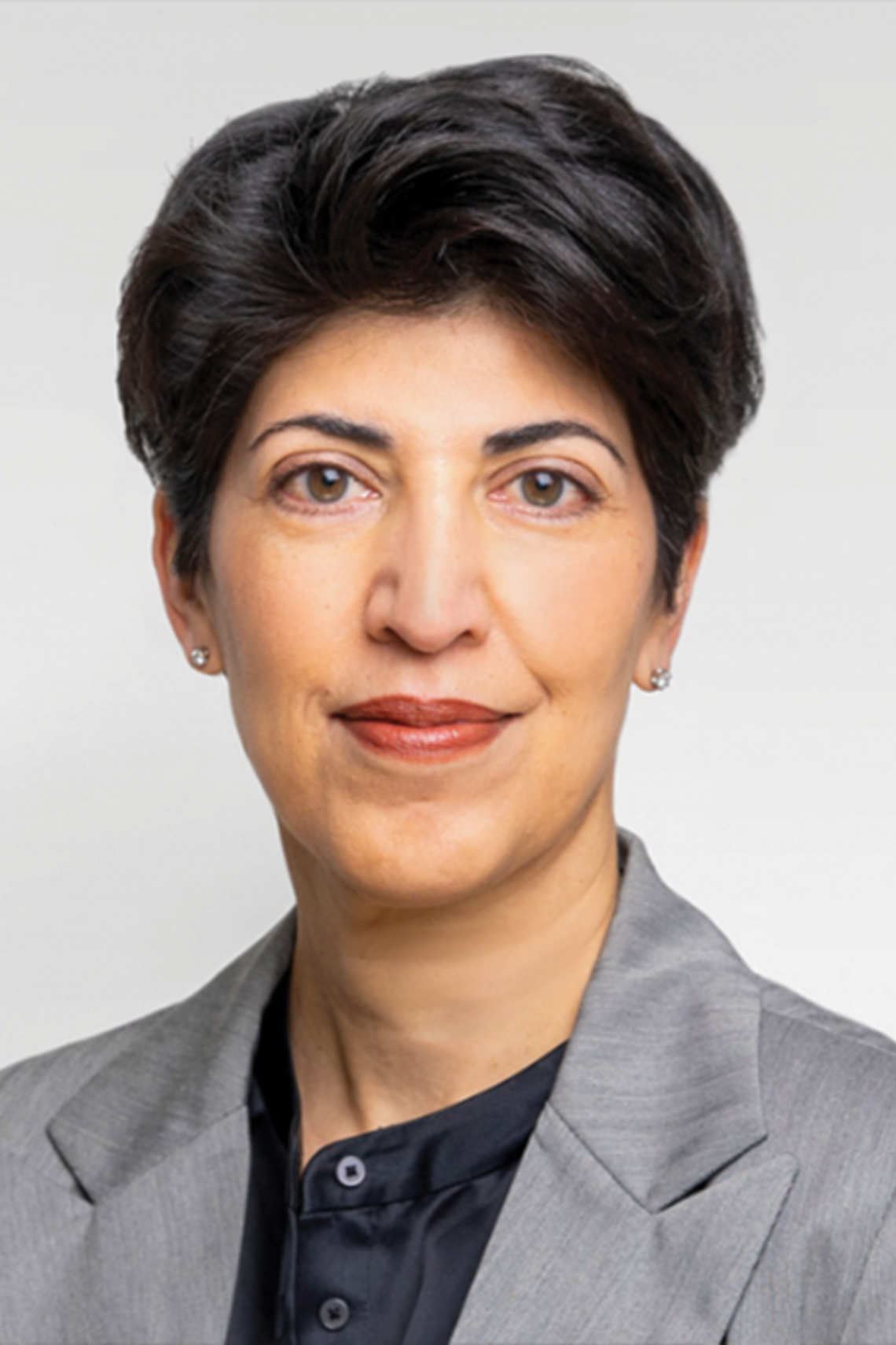 Professional headshot of Dr. Neesh Pannu, wearing a grey jacket and black blouse. She has short dark black hair and small earrings on. 