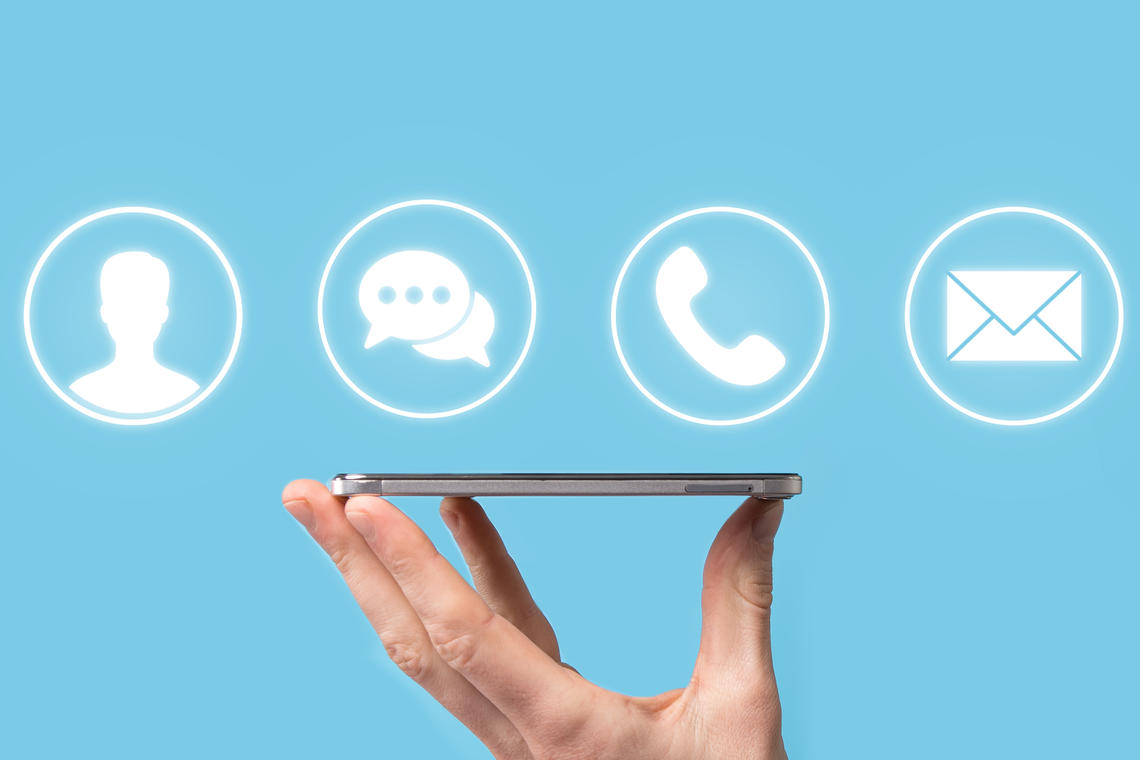 Hand holding iphone with contact icons above it