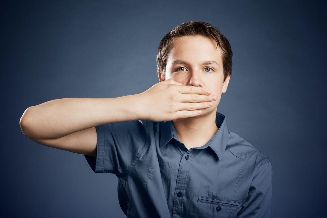 Boy with hand on mouth