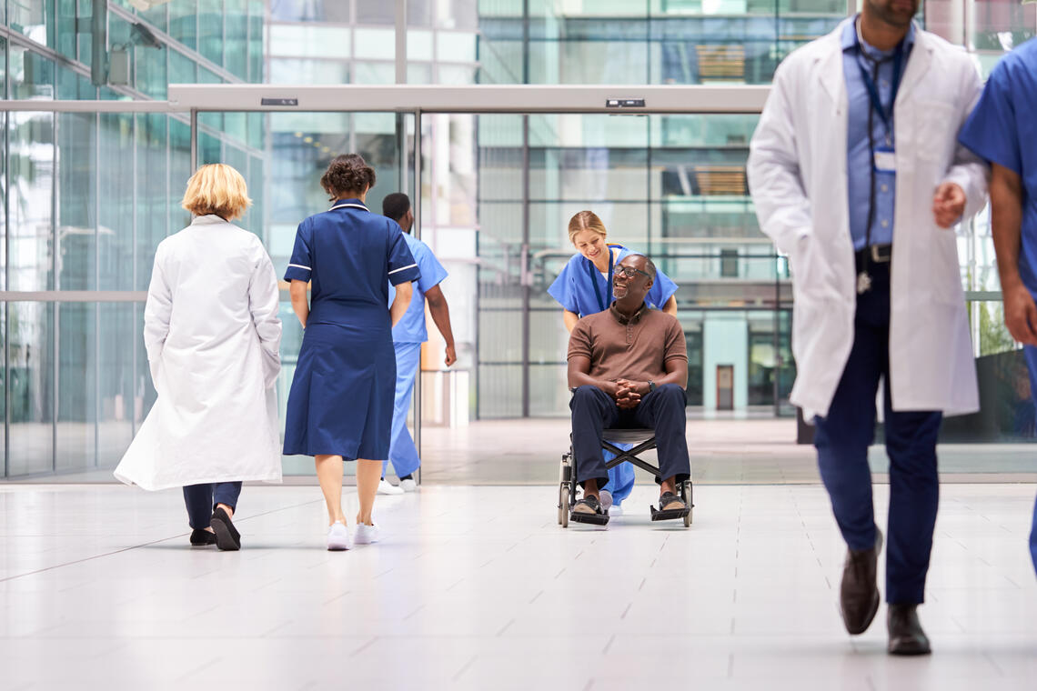 Black male patient in a wheel chair being pushed by a nurse