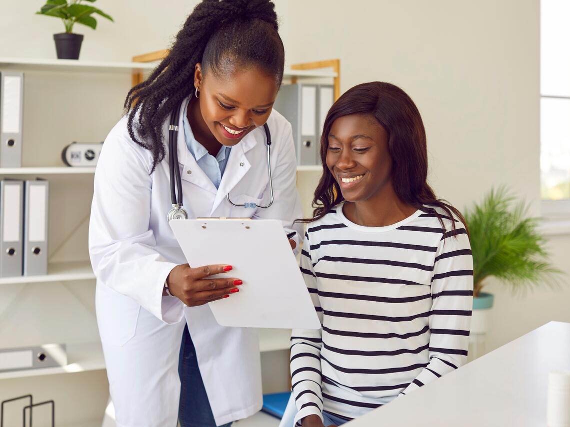 Female doctor showing her young female patient her medical charts