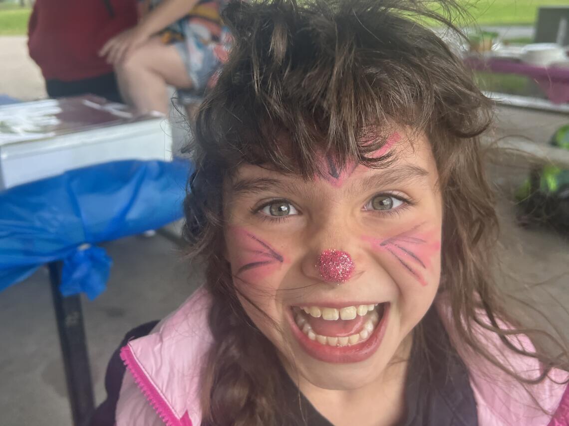young child with pink and purple face paint