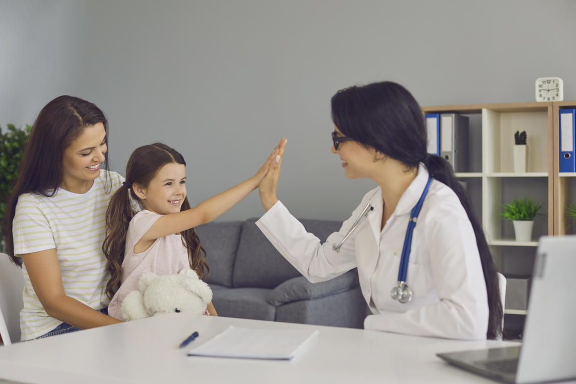 Family Doctor High fives child in clinic