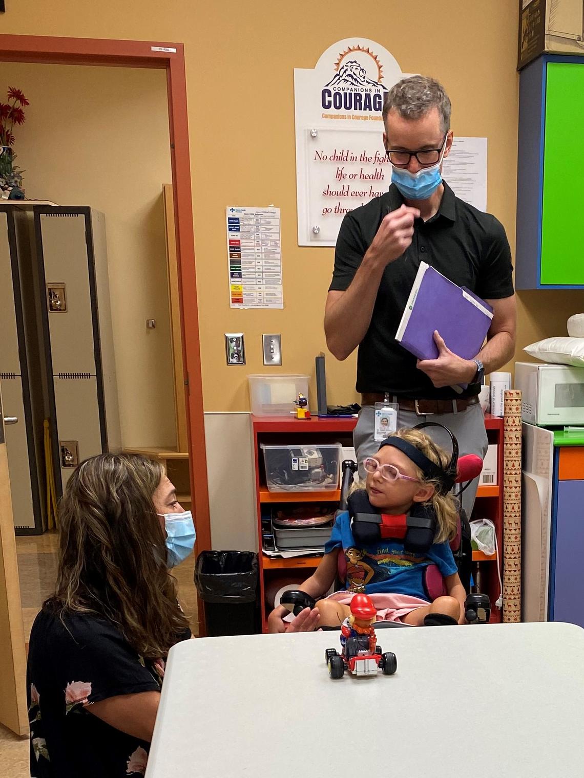 A girl using BCI to drive a remote control car with the help of a therapist and neurologist