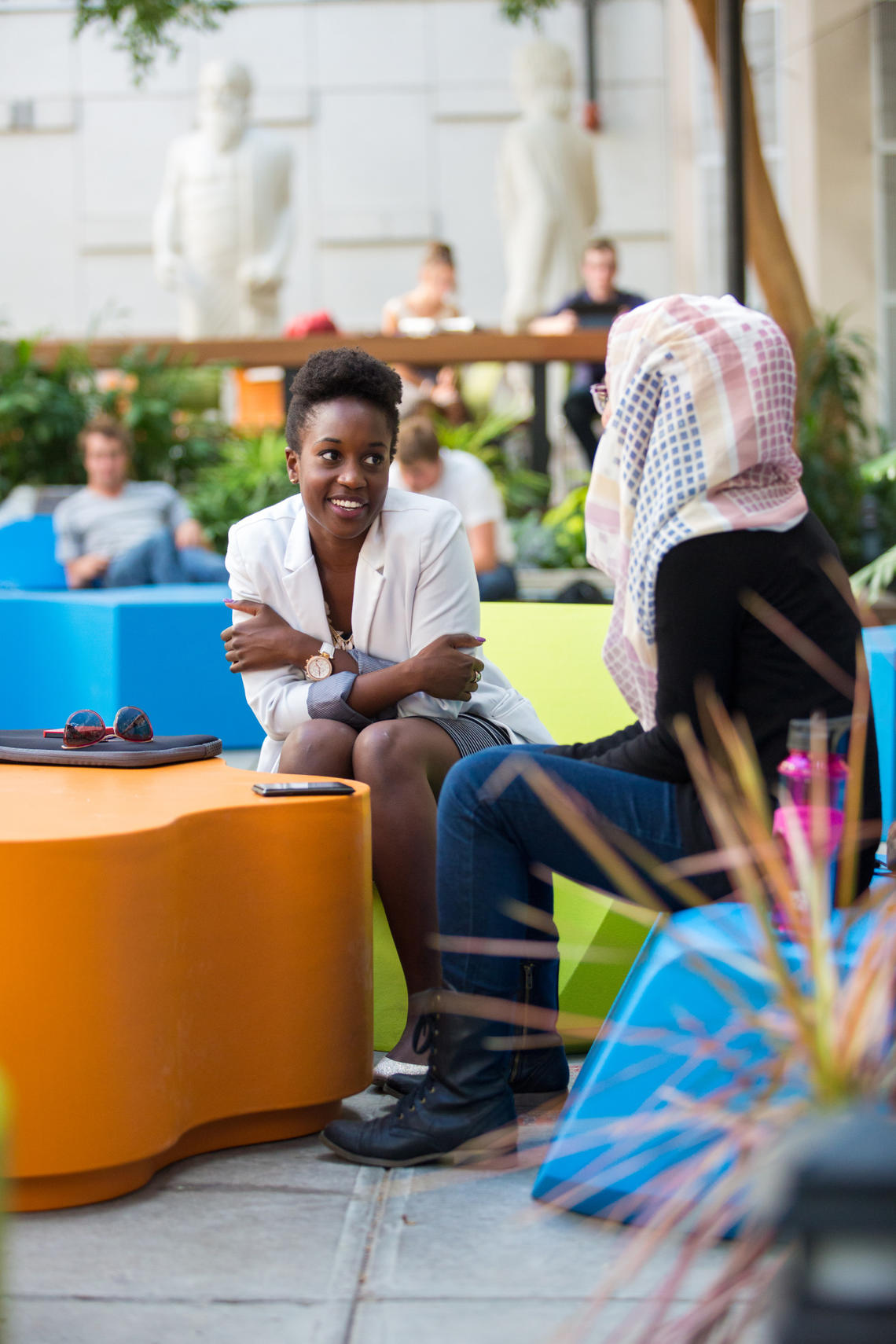 Two woman seated at colorful tables talking 