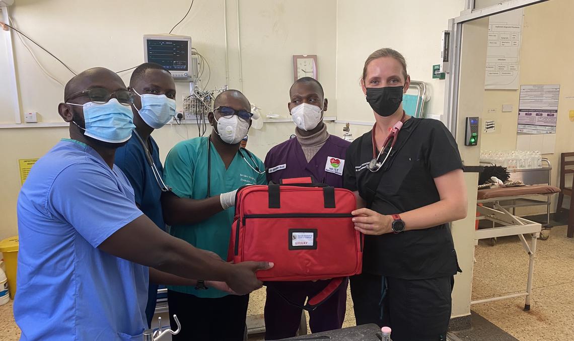 Five people standing together holding an emergency medical kit