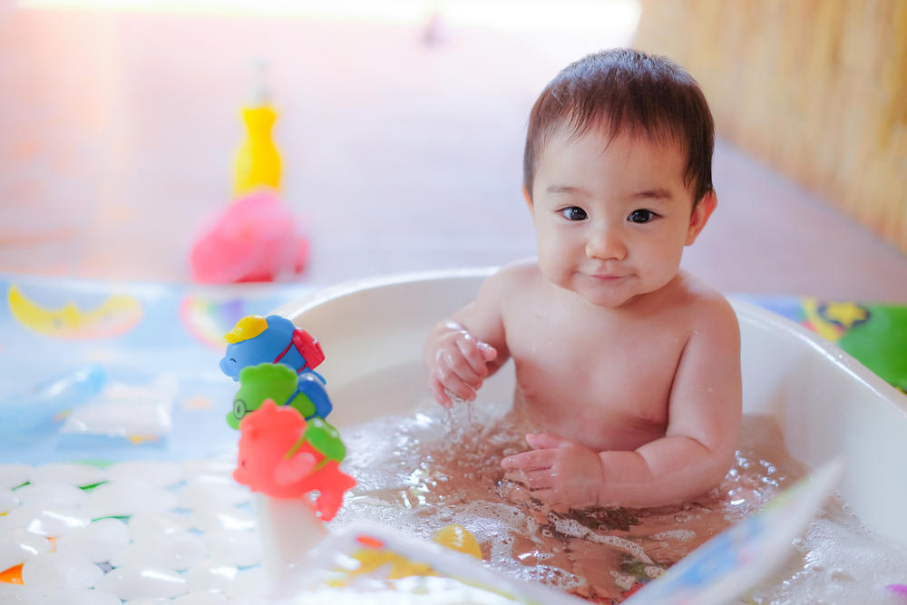 Baby sitting in bath with toys