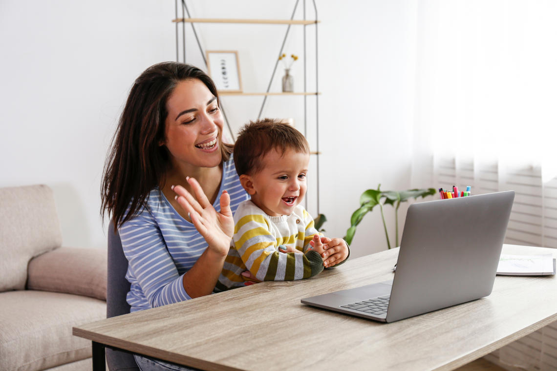 mom and toddler waving at computer