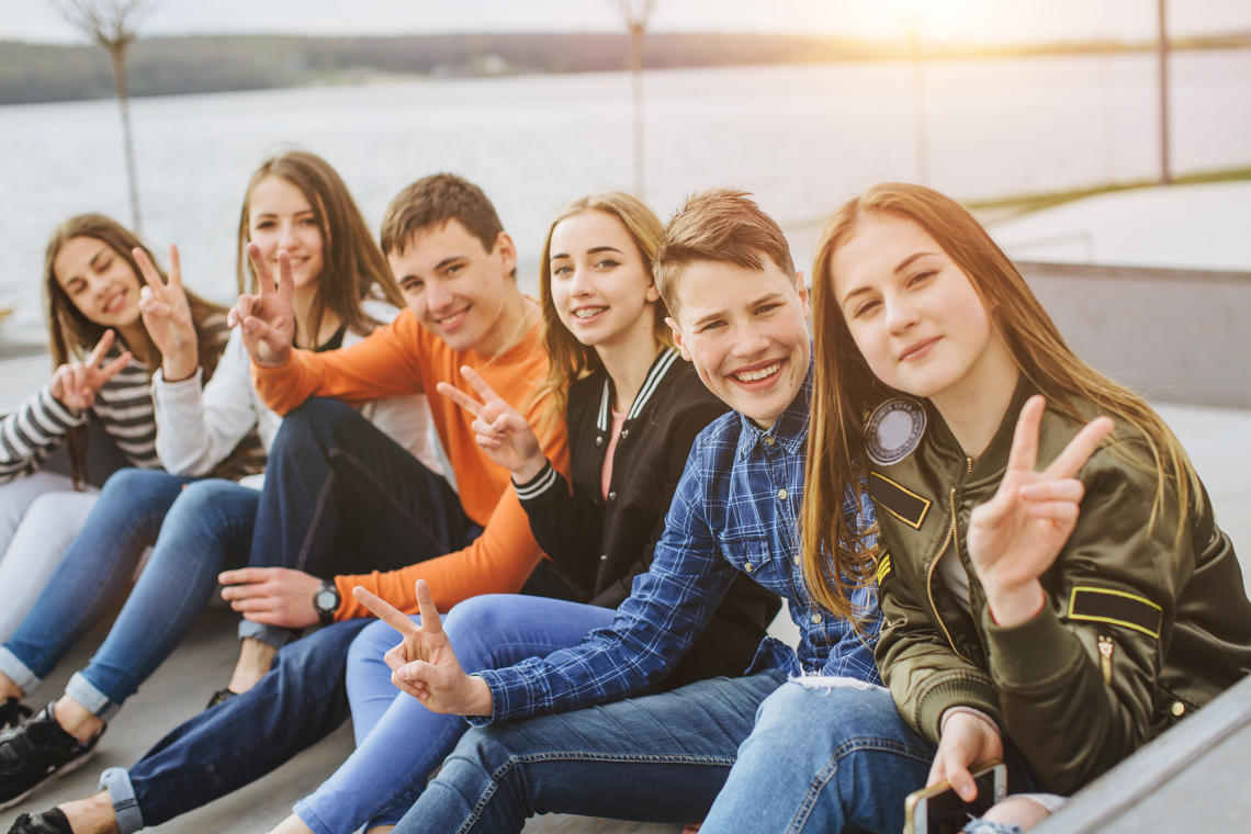 Teenage girls and boys sitting down next to each other